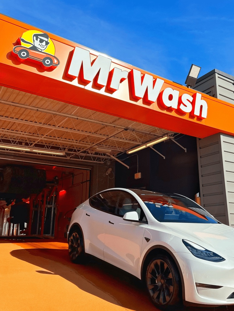 A freshly washed car rolling out under the Mr Wash sign in Tysons
